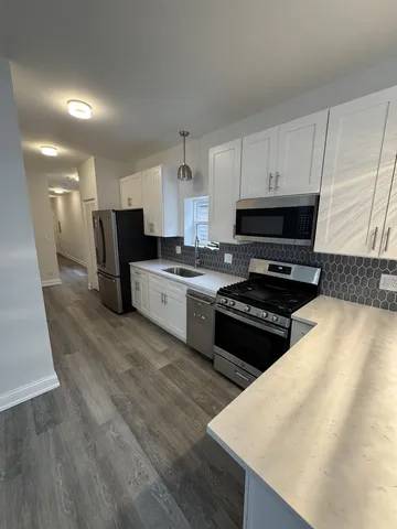 a kitchen with stainless steel appliances a stove a sink a microwave a refrigerator and cabinets