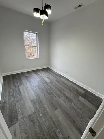 an empty room with wooden floor ceiling fan and windows