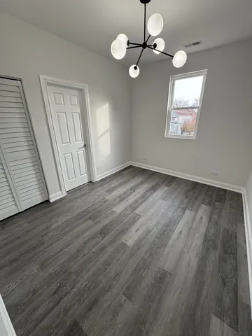 an empty room with wooden floor fan and window