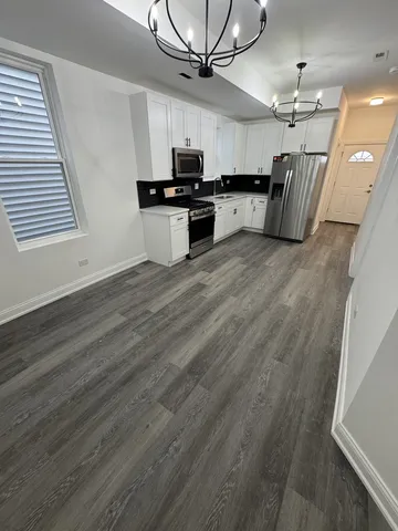 a kitchen with granite countertop a stove a sink dishwasher and a microwave oven on the kitchen countertops with wooden floor