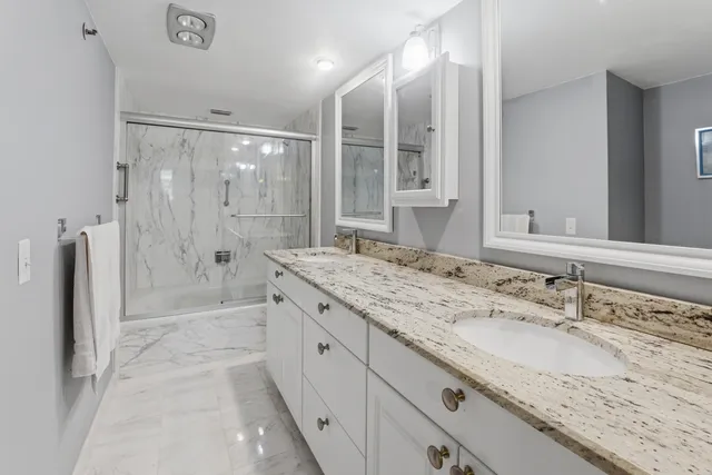 a bathroom with a granite countertop shower sink and mirror