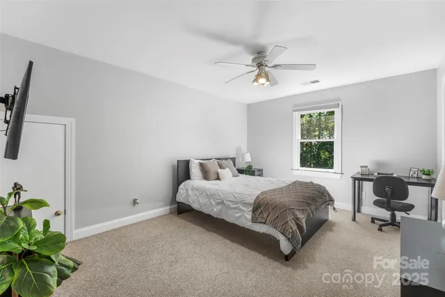 a spacious bedroom with a bed table chair and a window