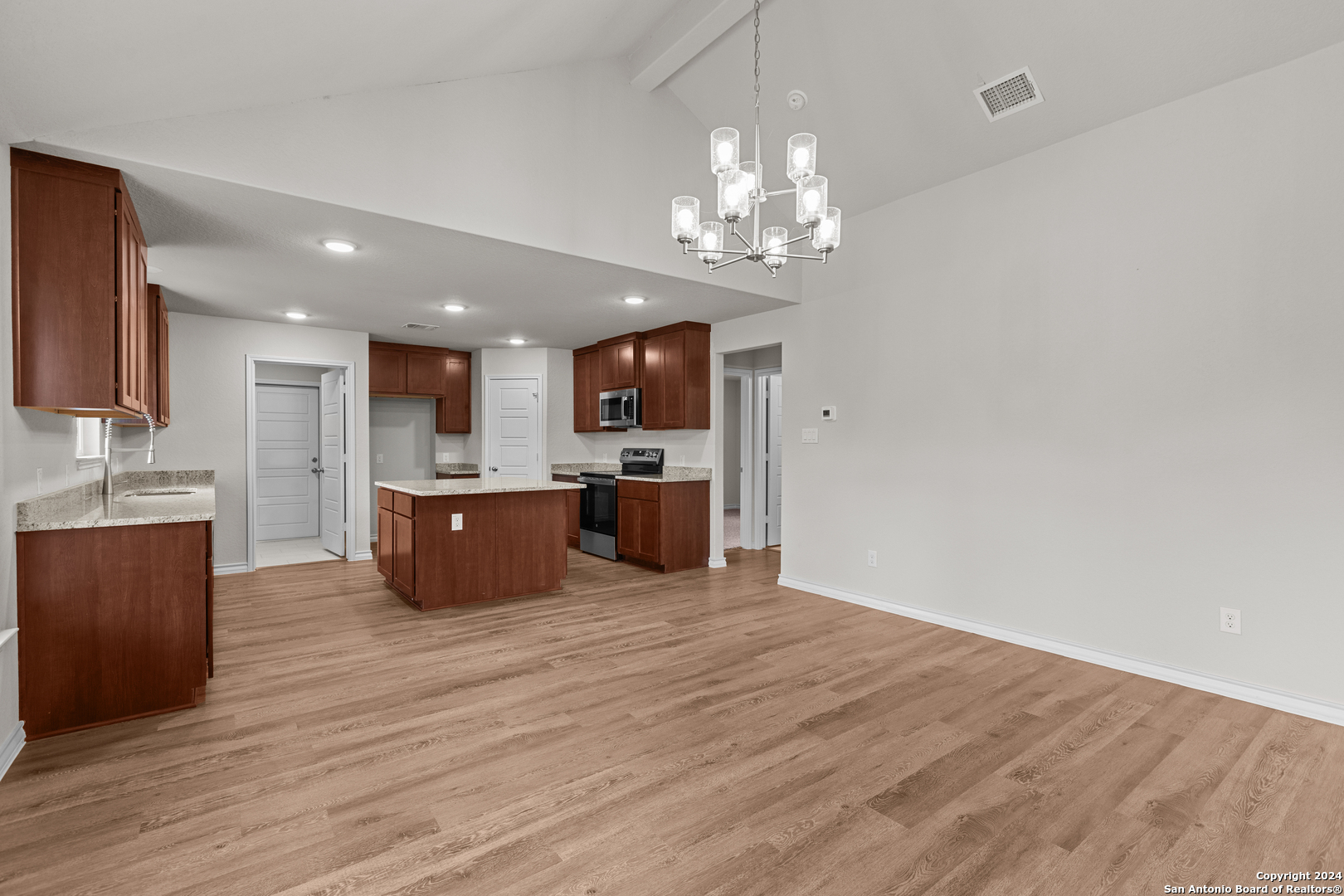117 Sylas Hayes Loop Pleasanton, TX 78064 - Photo 14 of 38 a large kitchen with kitchen island a island wooden floor stainless steel appliances and cabinets