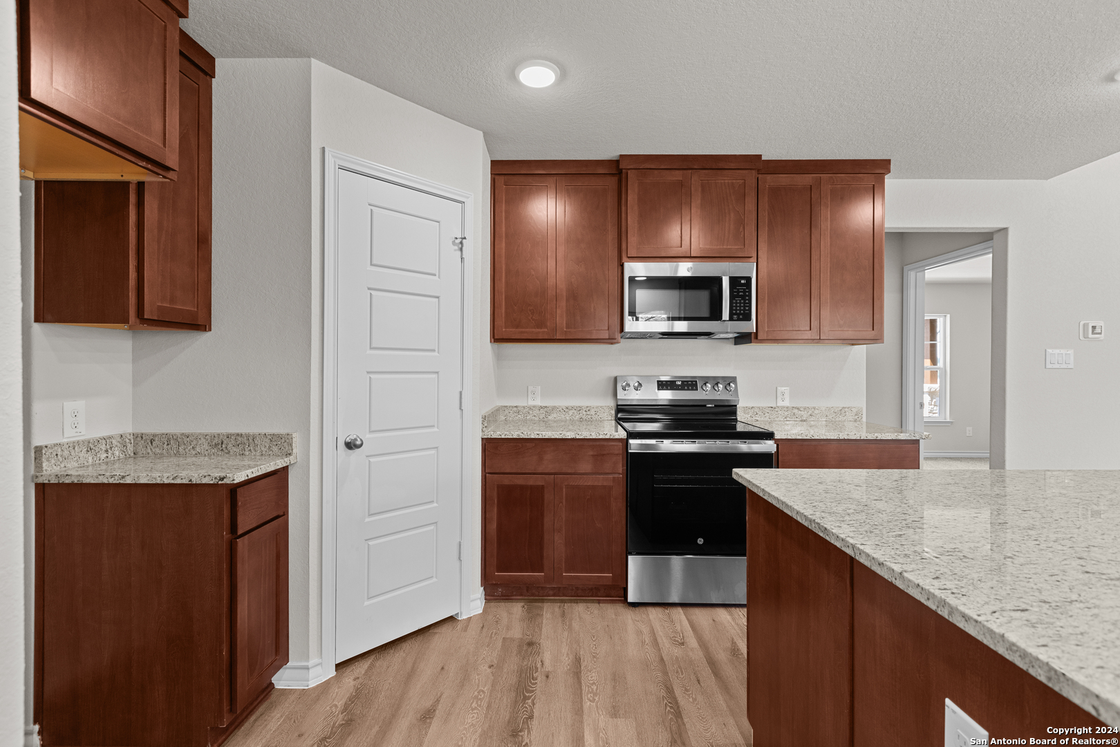 117 Sylas Hayes Loop Pleasanton, TX 78064 - Photo 21 of 38 a kitchen with granite countertop wooden cabinets and a stove top oven