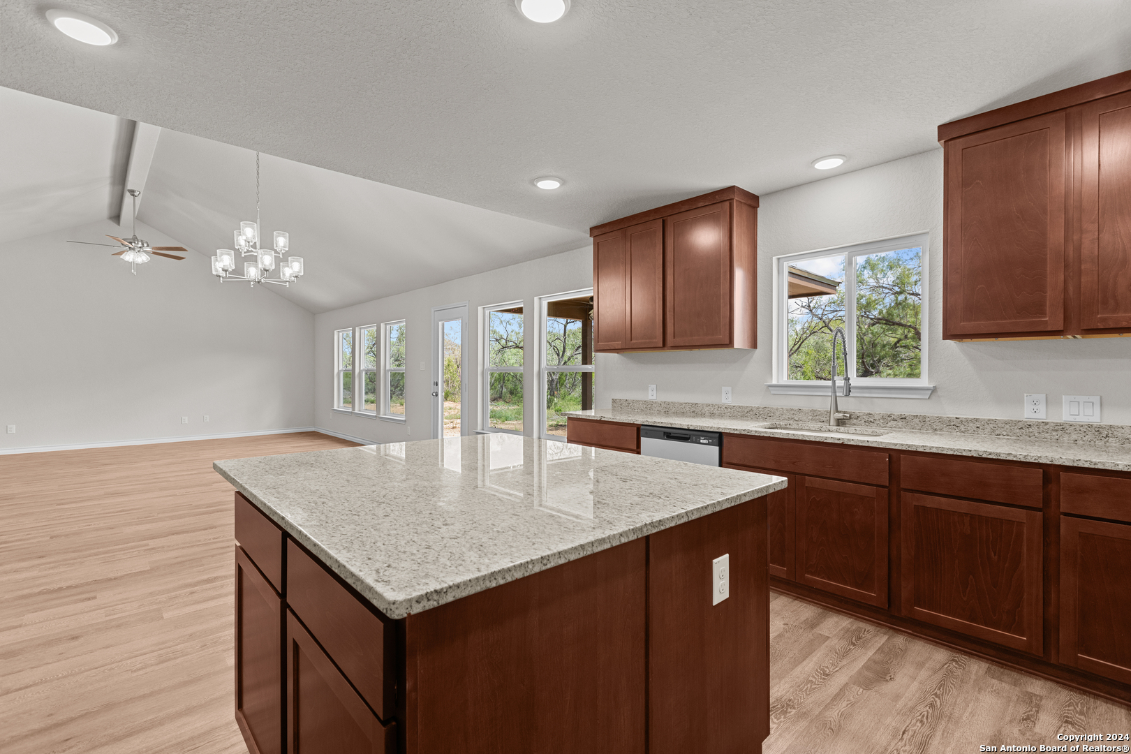 117 Sylas Hayes Loop Pleasanton, TX 78064 - Photo 22 of 38 a kitchen with a kitchen island a sink cabinets and wooden floor