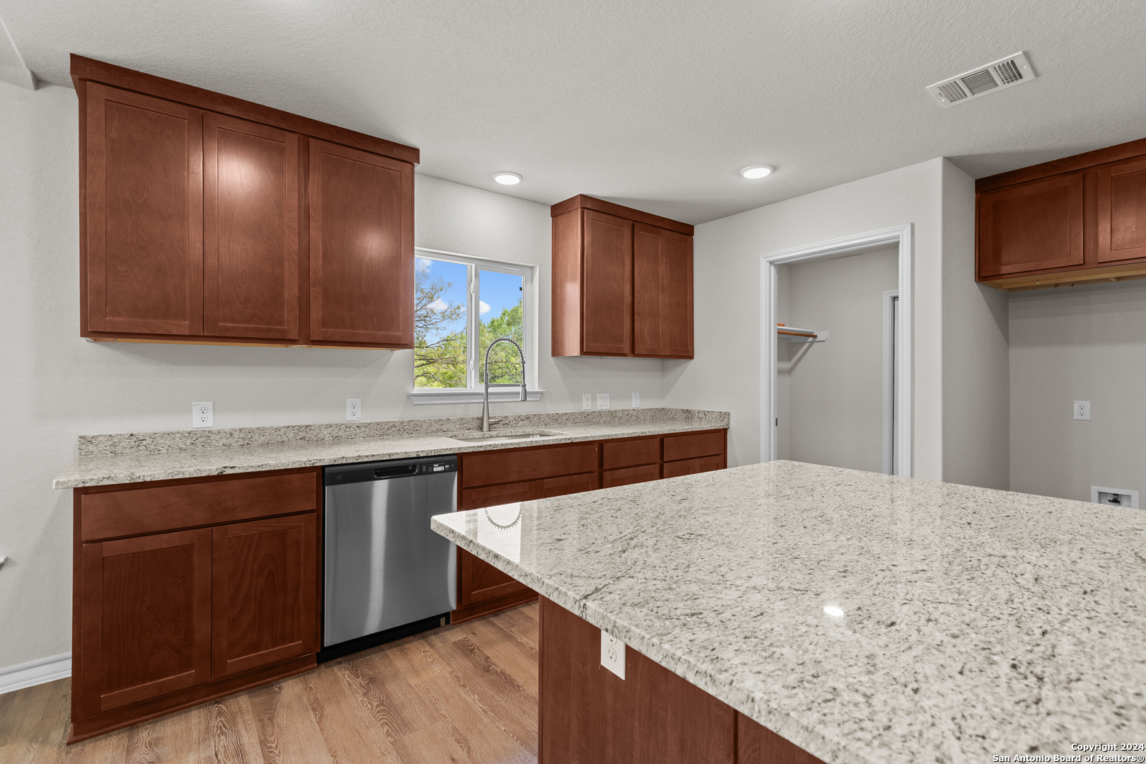 117 Sylas Hayes Loop Pleasanton, TX 78064 - Photo 24 of 38 a kitchen with stainless steel appliances granite countertop wooden cabinets a sink and dishwasher