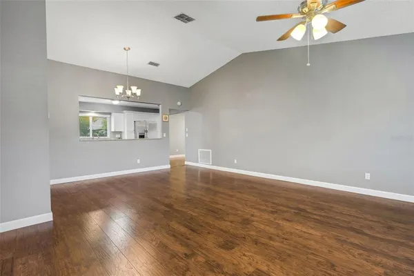 an empty room with wooden floor chandelier and windows