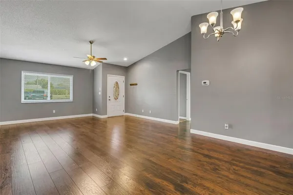 a dining room with wooden floor a chandelier a glass table and chairs