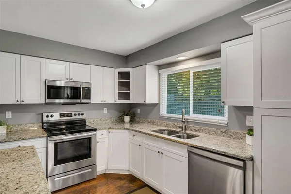 a kitchen with granite countertop stainless steel appliances a stove microwave and sink