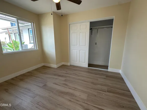 a view of an empty room with wooden floor and a window
