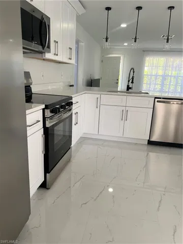 a kitchen with stainless steel appliances granite countertop a stove a sink and a microwave