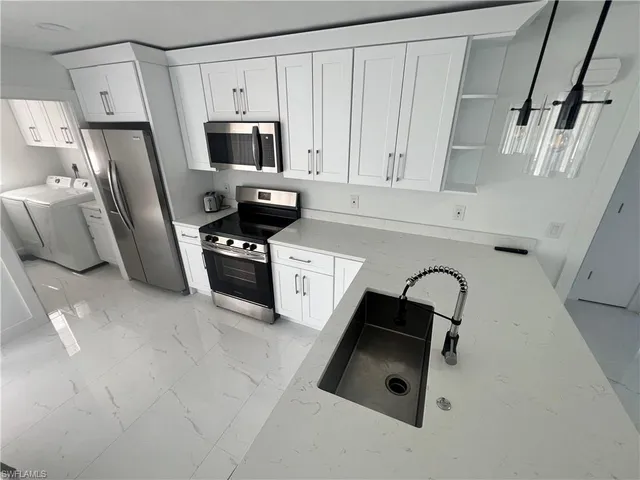 a kitchen with stainless steel appliances a refrigerator a sink a stove and white cabinets