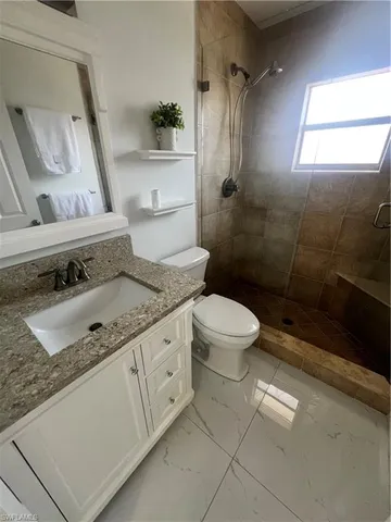 a bathroom with a granite countertop sink a toilet and shower