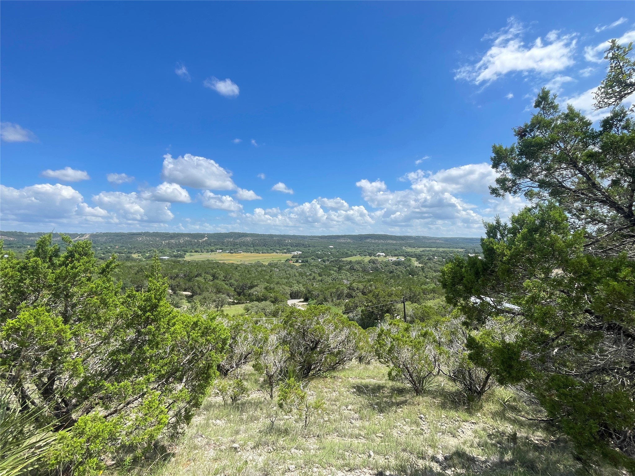 919 Little Ranches Road Wimberley, TX 78676 - Photo 13 of 13 Breathtaking natural panorama unfolds, revealing endless green hills under a vast blue sky.
