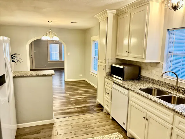 a kitchen with granite countertop a sink and white cabinets