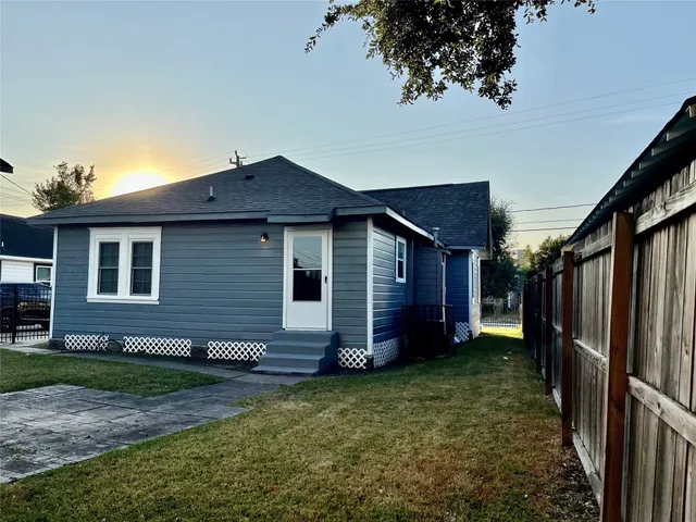 a view of a backyard with a large tree and wooden fence