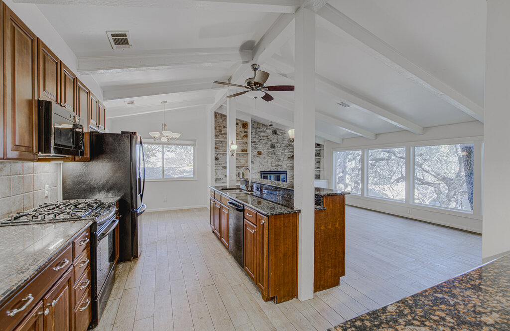 2400 Spring Creek Drive Austin, TX 78704 - Photo 38 of 38 Kitchen with black appliances, wood finish cabinets, dark stone counters, beam ceiling, and open floor plan