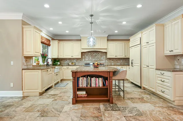 a kitchen with granite countertop a stove a sink a refrigerator and cabinets