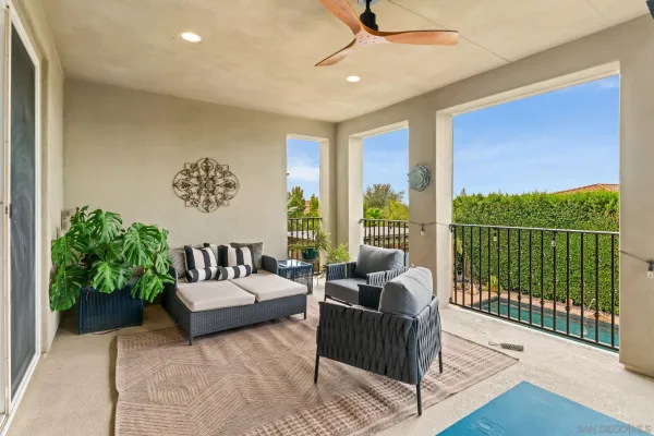 a view of a dining room and livingroom with furniture wooden floor a rug a flat screen tv a rug and a chandelier