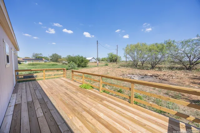 a view of swimming pool with wooden floor and large trees