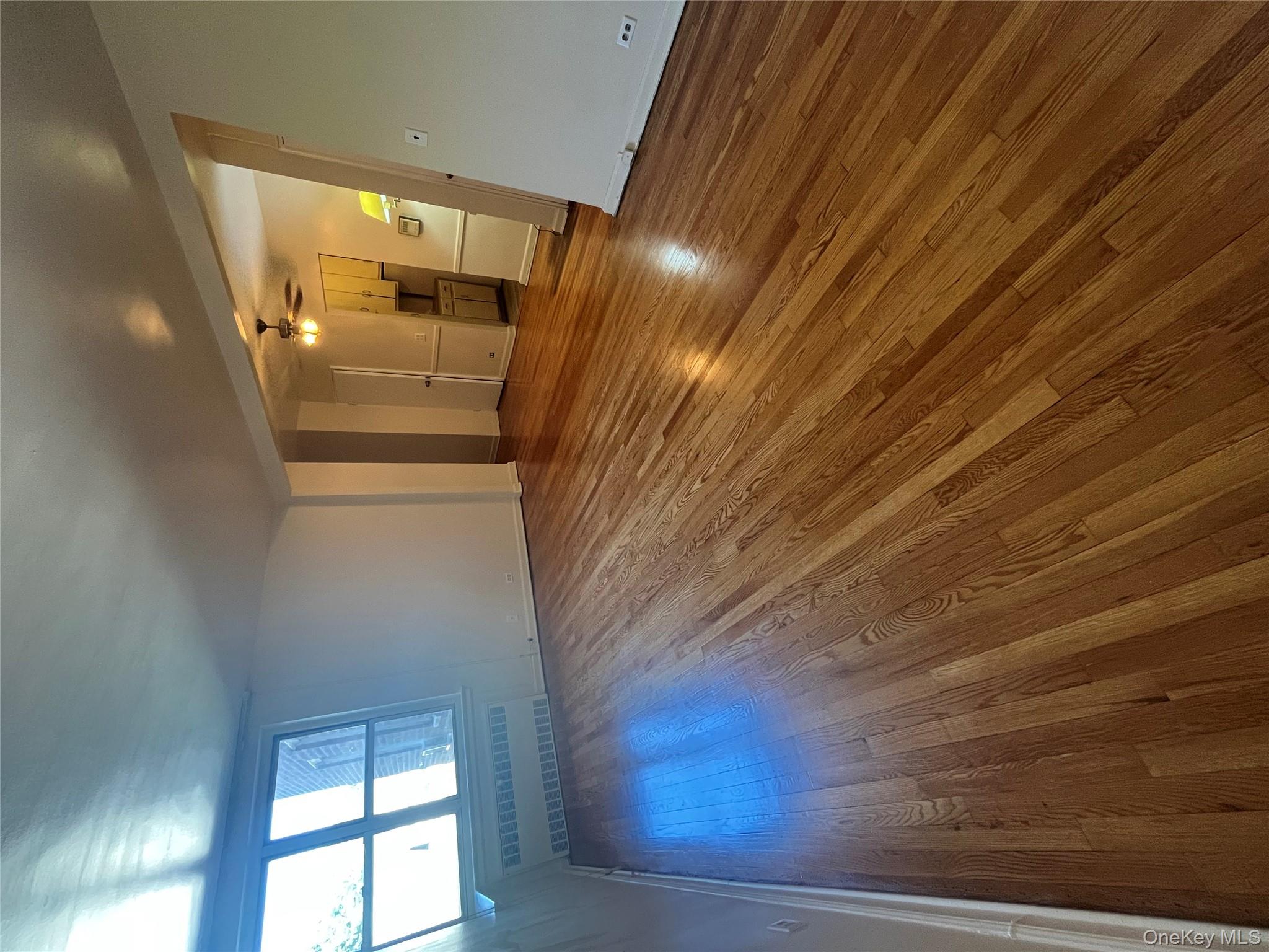 325 East 201st Street, Unit 4D Bronx, NY 10458 - Photo 17 of 22 Unfurnished living room featuring dark wood-style floors, radiator, and a ceiling fan