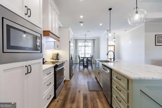 a kitchen with a stove a sink a kitchen island with wooden floor and cabinets