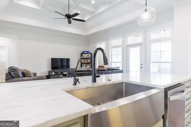 a kitchen with stainless steel appliances a sink a faucet a chandelier and living room view