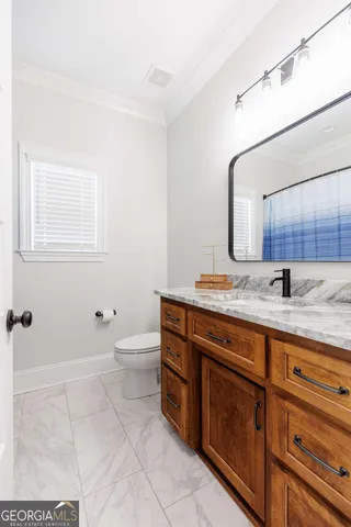 a bathroom with a granite countertop sink a toilet and mirror