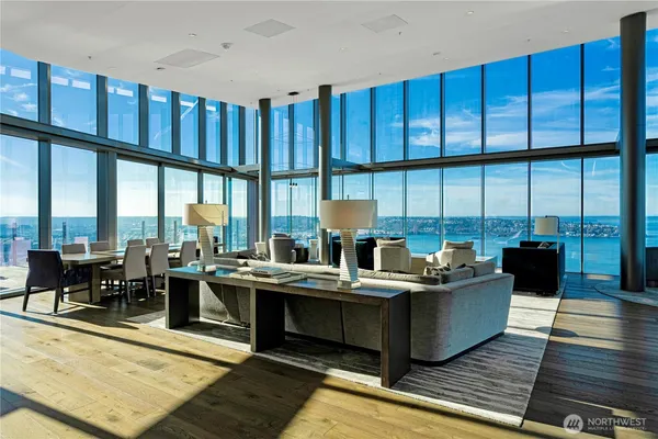 a living room with couches a coffee table and kitchen view with wooden floor
