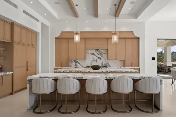 a kitchen with a dining table chairs sink and white cabinets