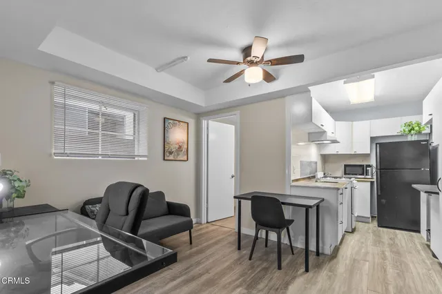 a kitchen with stainless steel appliances a refrigerator a sink dishwasher a stove and white cabinets with wooden floor