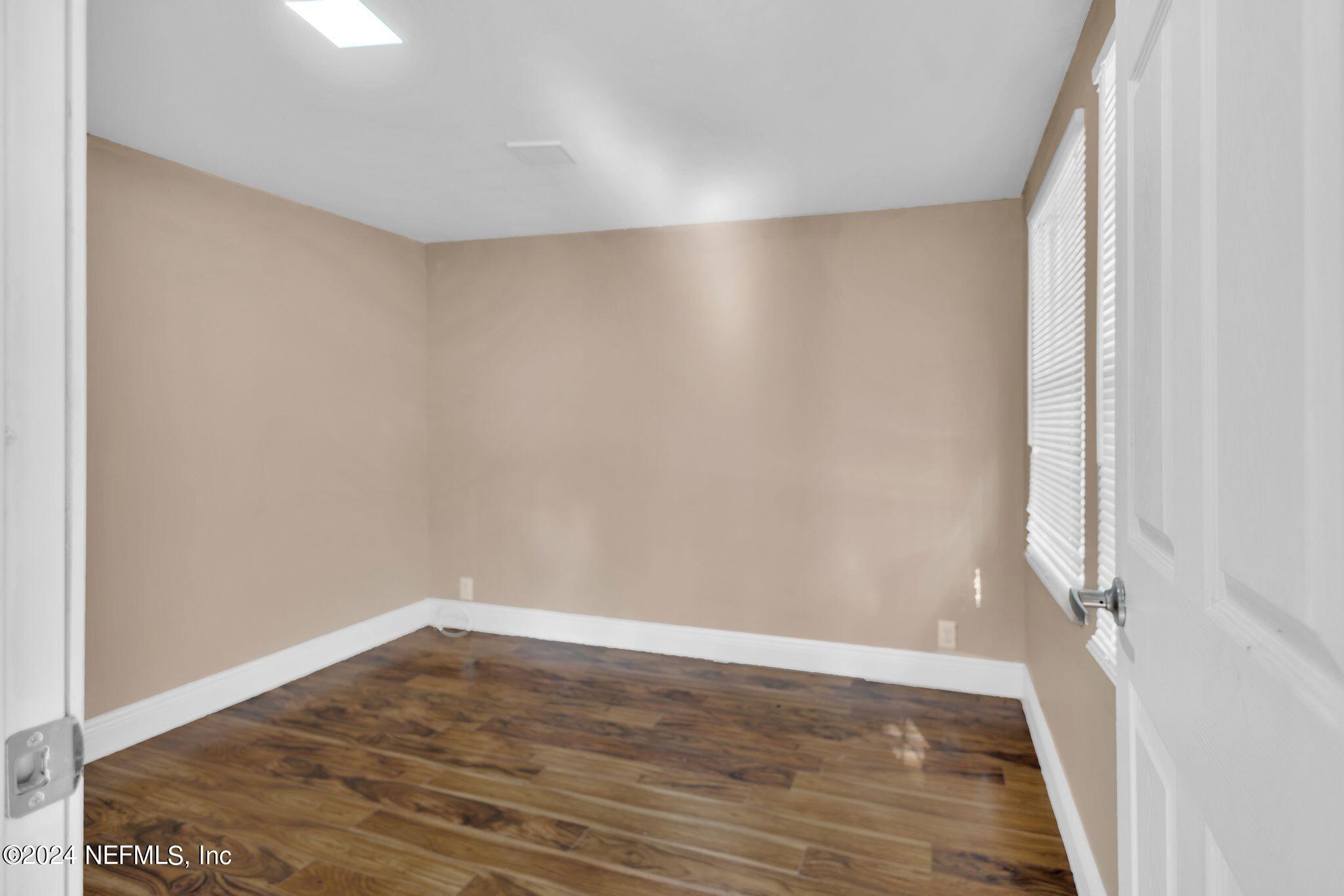 10357 Anson Road Jacksonville, FL 32246 - Photo 6 of 27 a view of an empty room with wooden floor and a window
