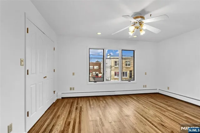 an empty room with chandelier fan and window