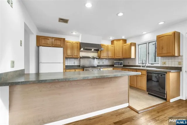 a kitchen with stainless steel appliances granite countertop a sink a stove and a refrigerator
