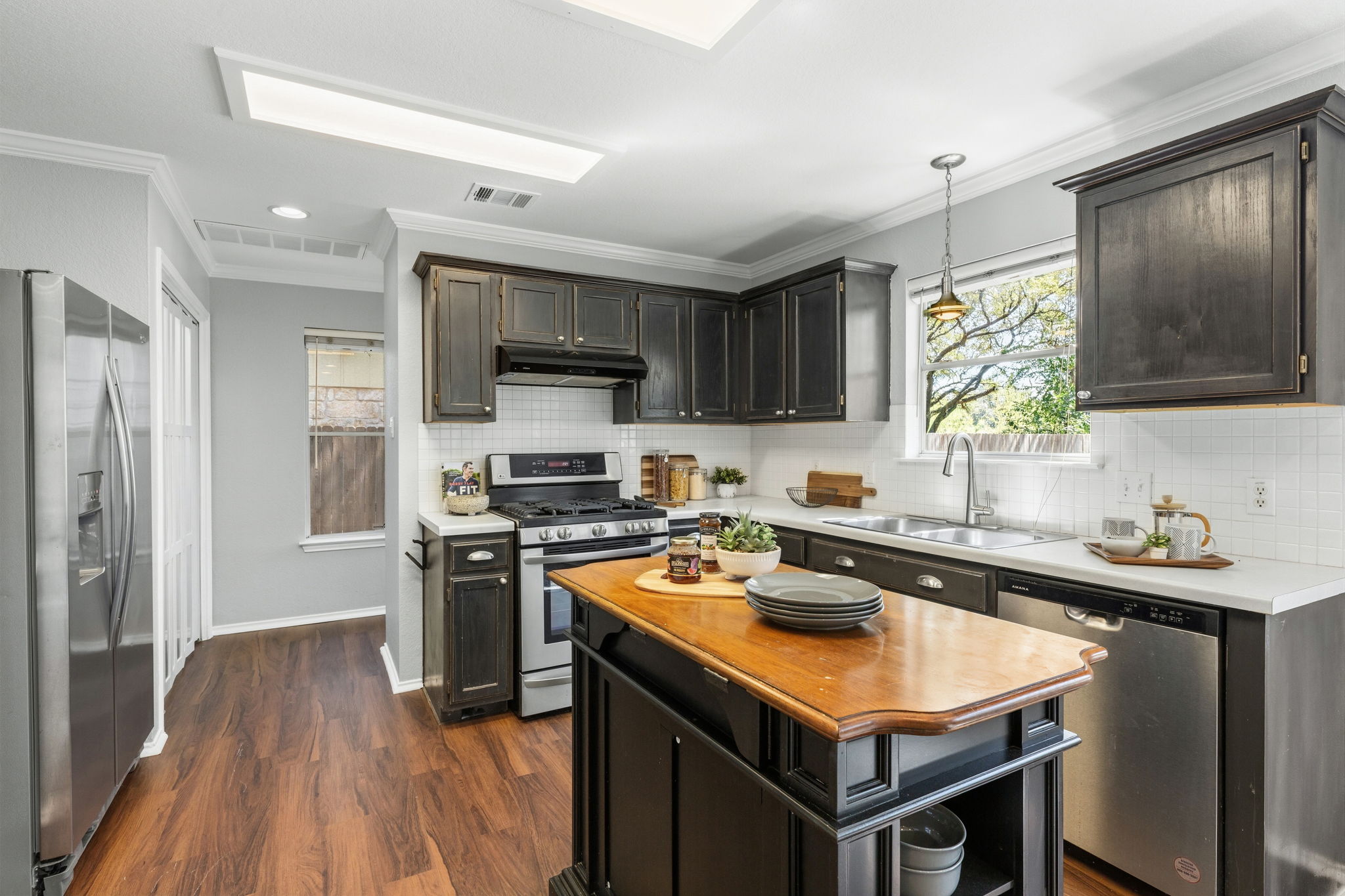 4609 Walsall Loop Austin, TX 78749 - Photo 10 of 39 Rich wood flooring contrasts with dark cabinetry and clean countertops in this well-appointed kitchen.