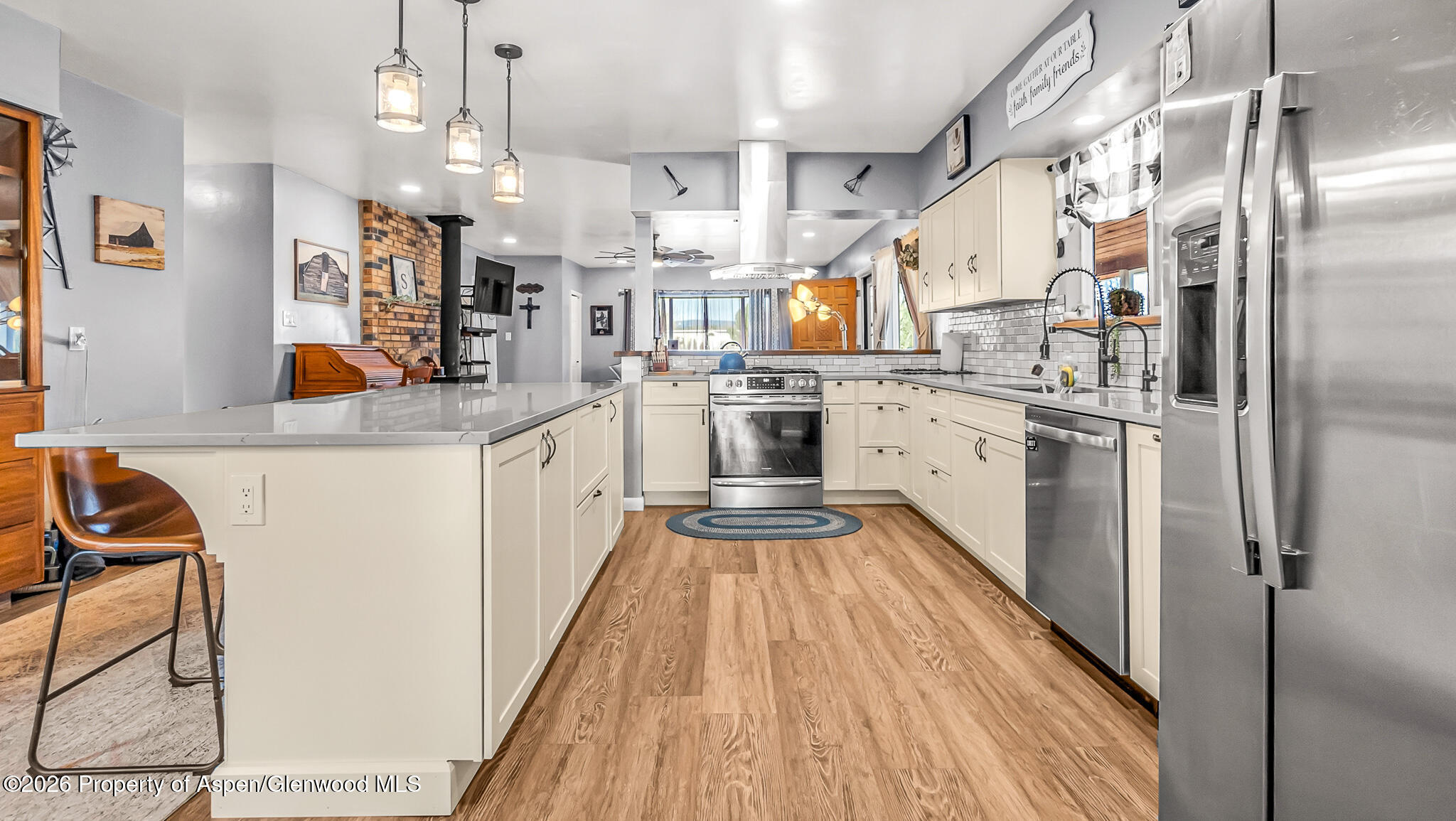 134 4th Street Meeker, CO 81641 - Photo 4 of 47 a large kitchen with stainless steel appliances kitchen island granite countertop a refrigerator a stove a sink dishwasher and white cabinets with wooden floor