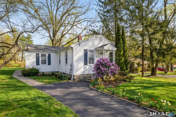 a front view of a house with a garden and trees
