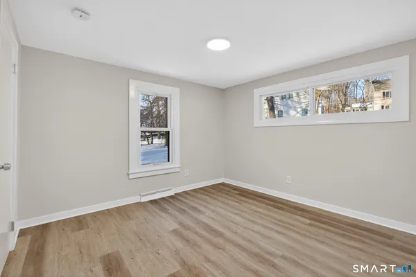 a view of an empty room with wooden floor and a window