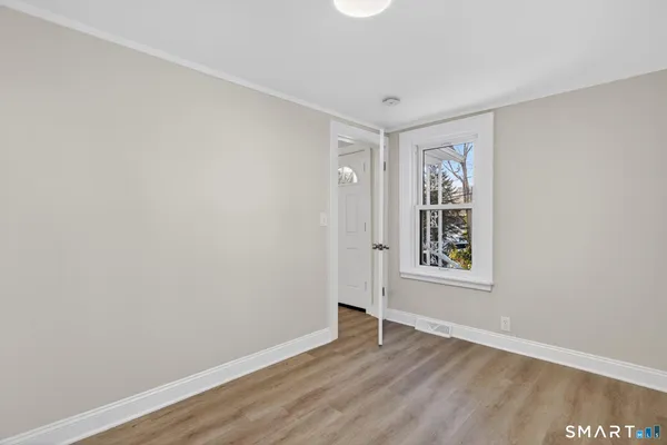 an empty room with wooden floor and windows