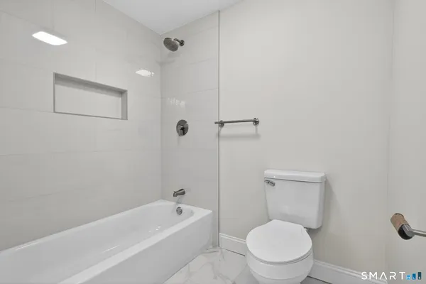 a white toilet sitting next to a bath tub and shower