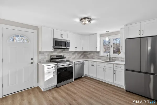 a kitchen with cabinets stainless steel appliances and a wooden floor