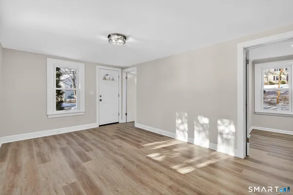 a view of an empty room with wooden floor and a window