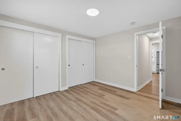 a view of an empty room with wooden floor and closet area
