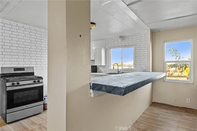 a kitchen with granite countertop a stove and a wooden floor