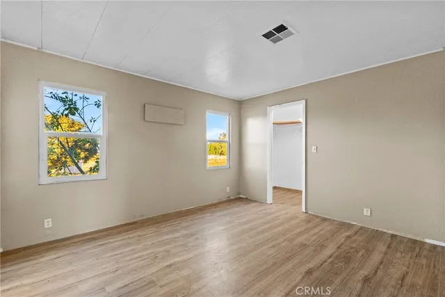 a view of an empty room with window and wooden floor