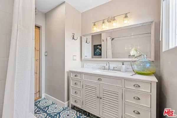 a bathroom with a granite countertop sink vanity mirror next to a window