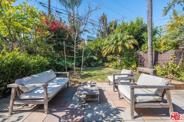 a view of a patio with couches table and chairs potted plants and palm trees