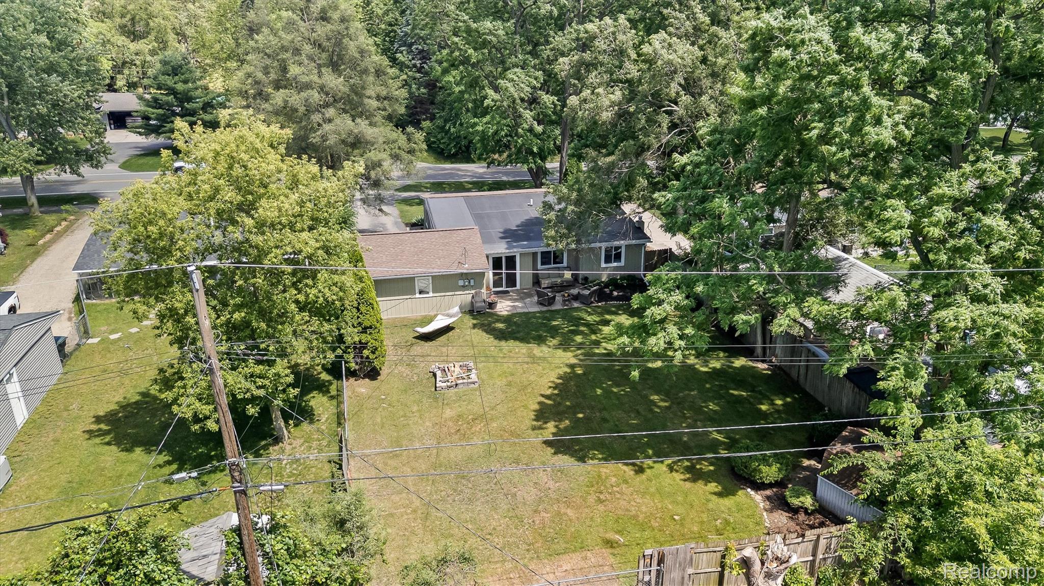 870 Pine Tree Road Lake Orion, MI 48362 - Photo 29 of 32 Expansive backyard featuring a large grassy area, mature trees, a patio area, and a fire pit