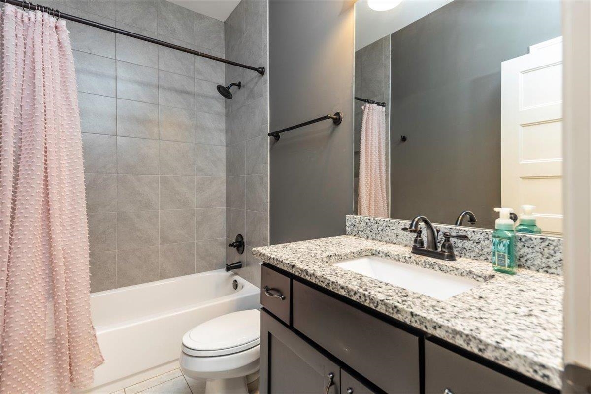 3328 Straw Bridge Road Olive Branch, MS 38654 - Photo 25 of 28 Granite-style countertop with an undermount sink, dark finish vanity, and gray wall tiling in the shower/tub combination