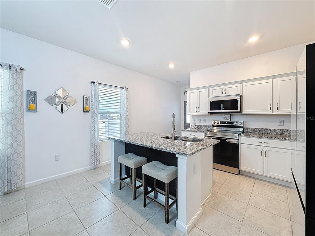 2030 Hemingway Circle Groveland, FL 34736 - Photo 6 of 21 a kitchen with stainless steel appliances kitchen island granite countertop a sink and cabinets